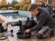 Hausbesitzer entleert eine vom Strom getrennte Poolpumpe vor der frostfreien Winterlagerung